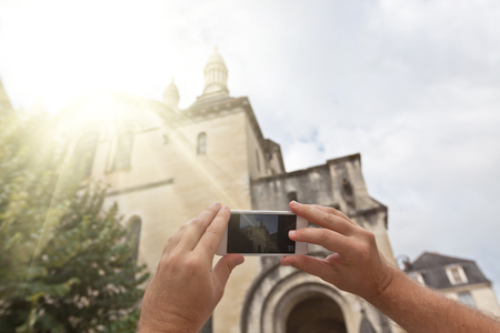 Tourist hands holding smart phone taking photo of Perigueux, Franceの写真素材
