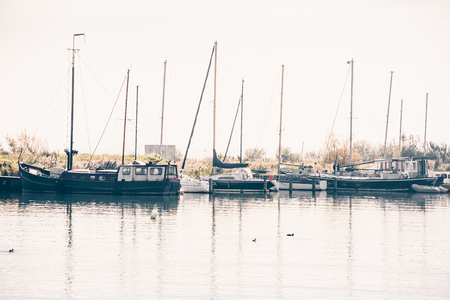 Harbor of a dutch village with sailing yachts moored to a pierの写真素材