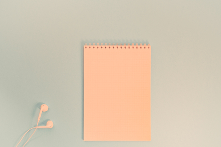 Creative flat lay photo of workspace desk with paper notebook, smartphone, earpieces, pen and coffee with copy space background minimal styleの写真素材