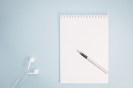 Creative flat lay photo of workspace desk with paper notebook, smartphone, earpieces, pen and coffee with copy space background minimal styleの写真素材