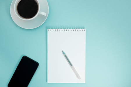 Creative flat lay photo of workspace desk with paper notebook, smartphone, earpieces, pen and coffee...