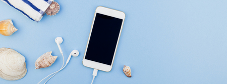 Creative long wide banner flat lay concept of summer travel vacations. Top view of beach towel, seashells, starfish and smartphone on pastel blue background with copy space in minimal style, templateの写真素材