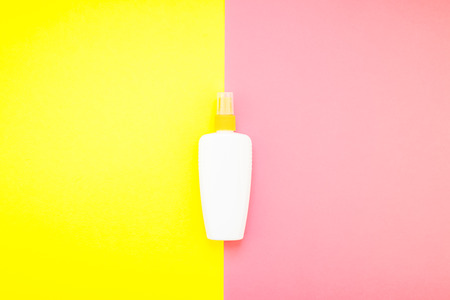 Sunscreen blank bottle mockup on bright yellow and pink duotone paper background. Summer vacations creative flat lay concept template for textの写真素材