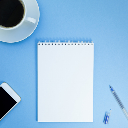 Creative square flat lay photo of workspace desk with paper notebook, smartphone, pen and coffee...