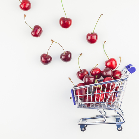 Square image of ripe cherries in a shopping cart with copy space isolated on white background in minimal style.の写真素材