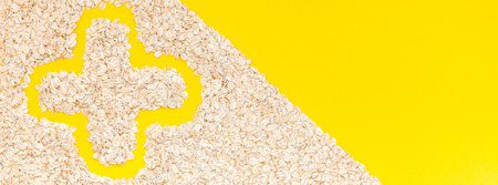 Creative flat lay concept top view of oatmeal flakes for healthy and vegetarian organic food for breakfast on a bright yellow color paper long wide banner with copy space in minimal styleの写真素材