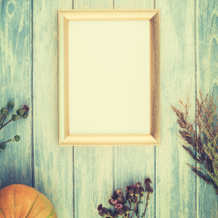 Square Top view of autumn orange pumpkins and dry flowers with grass thanksgiving background over blue toned wooden table with golden frame mock up and copy space in rustic style, template for textの写真素材
