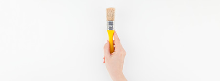 Long wide banner of woman hand holding new paint brush with copy space isolated on white background...