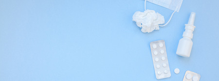 Creative flat lay concept of seasonal spring allergy with napkins, pills, face mask and drops in a bottle with copy space long wide banner minimal style, template for textの写真素材