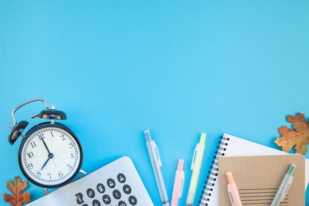 Creative flat lay top view back to school concept with alarm clock, color school and office supplies on bright turquoise paper table frame background with copy space, template for text or designの写真素材