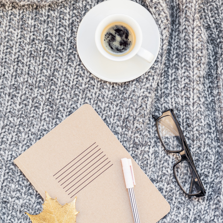 Creative square autumn flat lay overhead top view stylish home workspace with notebook coffee cup cozy gray knitted plaid background copy space. Fall season template for feminine blog social mediaの写真素材