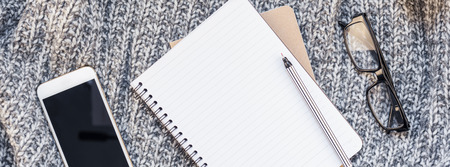 Creative autumn flat lay overhead top view stylish home workspace  smartphone notebook cozy gray knitted plaid long wide banner copy space. Fall season template feminine blog social mediaの写真素材