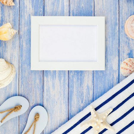 Square Creative flat lay concept summer travel vacations. Top view of towel flip flops seashells and starfish on pastel blue wooden planks background with copy space rustic style frame template textの写真素材
