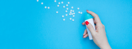 New Year or Christmas top view Xmas holiday celebration woman hand red manicure with spray bottle making snowflakes copy space turquoise blue color paper background minimal style Long wide bannerの写真素材