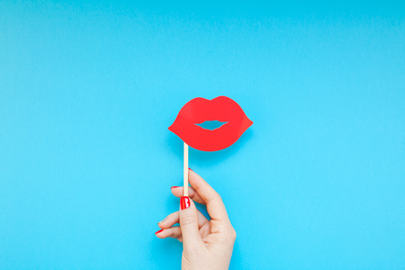 Creative overhead top view retro stylish red paper photo booth props female lips in hand turquoise background copy space.の写真素材