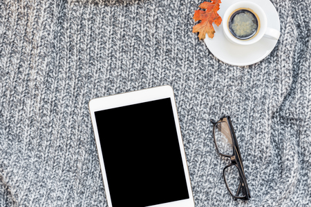 Creative autumn flat lay overhead top view stylish home workspace with tablet notebook coffee cup cozy gray knitted plaid background copy space.の写真素材