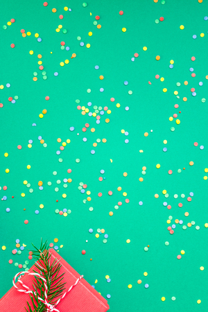 New Year or Christmas pattern flat lay top view with red alarm clock twelve midnight fir tree branch Xmas holiday celebration green paper bright colorful confetti background.の写真素材