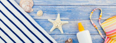 Long wide banner flat lay concept of summer travel vacations. Top view of beach towel sunscreen...