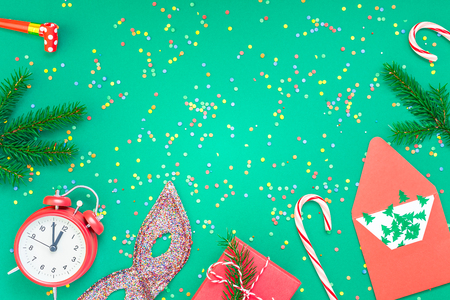 New Year or Christmas pattern flat lay top view with red alarm clock twelve midnight fir tree branch Xmas holiday celebration green paper bright colorful confetti background.の写真素材