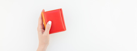 Woman hand with pastel manicure polish holding bright red leather wallet isolated on white background copy space in minimalism style. Long wide banner for feminine beauty blog social financial mediaの写真素材