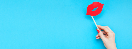 Creative overhead top view retro stylish red paper photo booth props female lips in hand turquoise background copy space. Birthday parties and weddings valentine day template. Long wide bannerの写真素材