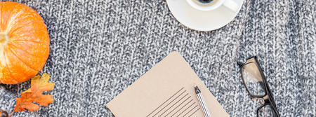 Creative autumn flat lay overhead top view stylish home workspace with notebook coffee cup cozy gray knitted plaid long wide banner copy space. Fall season template for feminine blog social mediaの写真素材