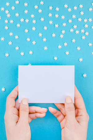 Creative Top view flat lay winter frame. Ð¡oncept Winter pattern made small white snowflakes letter woman hands pastel blue background copy space minimalism Template anniversary design invitation cardsの写真素材
