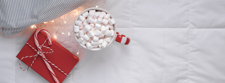 New Year or Christmas flat lay top view with Hot cacao coffee chocolate with marshmallows mug Xmas holiday celebration red present box bed with lights Concept blog social media 2019 Long wide bannerの写真素材