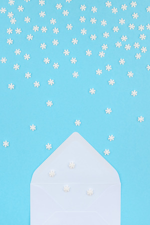 Creative Top view flat lay winter frame. Concept Mockup pattern made of small white snowflakes letter envelope pastel blue background copy space minimalism Template anniversary design invitation cardsの写真素材