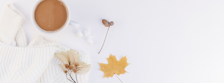 Creative autumn flat lay overhead top view coffee cup warm knitted sweater on white background copy space minimal style Fall winter season template for feminine blog social media Long wide bannerの写真素材