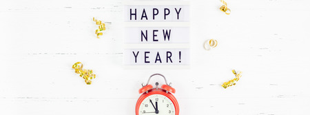 New Year or Christmas pattern flat lay top view red alarm clock twelve midnight Xmas holiday celebration white wooden golden sparkles confetti background. Template for your text design 2019の写真素材
