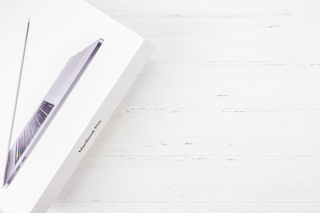 BERLIN, GERMANY - DECEMBER 09, 2018: The box of the latest Apple Macbook Pro laptop computer against white wooden background. Unboxing top view concept with copy spaceのeditorial素材