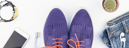 Long wide banner Flat lay of suede shoes, blue jeans, bracelets cactus and smartphone headphones on white background with copy space. Overhead view of woman casual outfit. Trendy hipster look top viewの写真素材