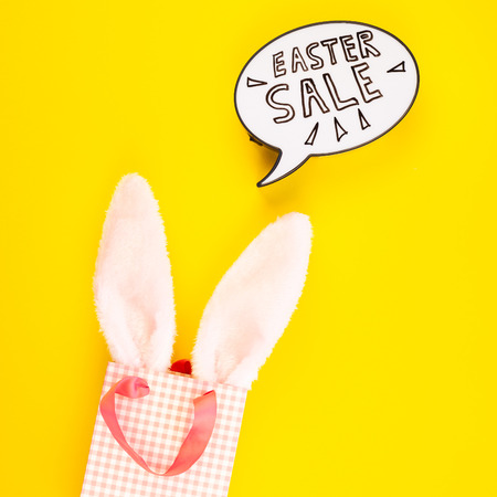 Creative Top view flat lay holiday promo composition Easter sale bunny ears eggs text message on bold yellow paper background copy space Template Easter day seasonal minimal conceptの写真素材