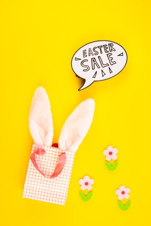 Creative Top view flat lay holiday promo composition Easter sale bunny ears eggs text message on bold yellow paper background copy space Template Easter day seasonal minimal conceptの写真素材