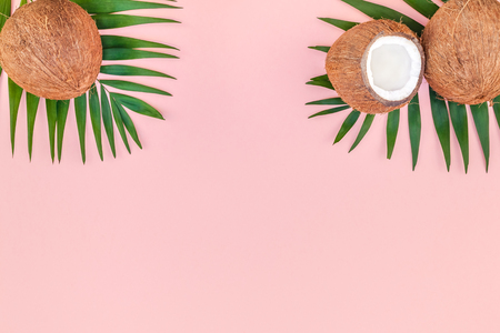Creative flat lay top view of green tropical palm leaves coconut fruits and coconut oil cosmetics for skin and hair care on pink paper background copy space. Minimal tropical summer beauty spa conceptの写真素材