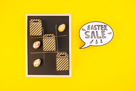 Creative Top view flat lay holiday promo composition Easter sale bunny ears gift boxes eggs text message on bold yellow paper background copy space Template Easter day seasonal minimal conceptの写真素材