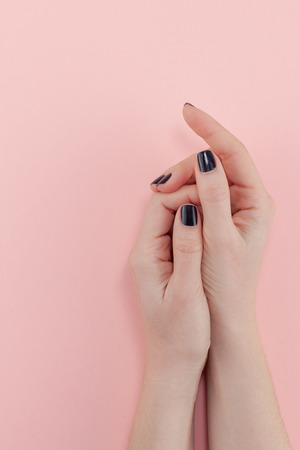 Stylish trendy female black manicure. Beautiful young woman's hands on millennial pink pastel background. Beauty and SPA concept. Template for feminine blog social mediaの写真素材