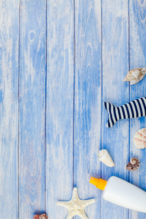Creative flat lay concept summer travel vacations. Top view of sunscreen bottle mockup seashells and starfish on pastel blue wooden planks background copy space in rustic style, frame template textの写真素材