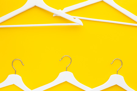 Creative top view flat lay white wooden hangers isolated bold yellow background with copy space minimalism style. Template fashion feminine blog social media sale store promo design shopping conceptの写真素材