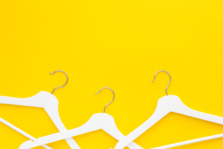 Creative top view flat lay white wooden hangers isolated bold yellow background with copy space minimalism style. Template fashion feminine blog social media sale store promo design shopping conceptの写真素材