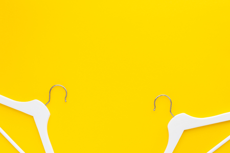 Creative top view flat lay white wooden hangers isolated bold yellow background with copy space minimalism style. Template fashion feminine blog social media sale store promo design shopping conceptの写真素材