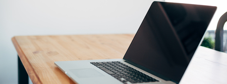 Comfortable working place in home office with wooden table and modern laptop laying on it. Freelance...