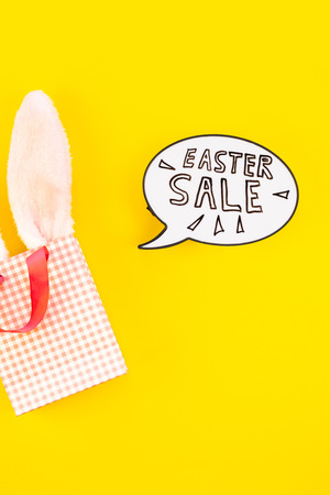 Creative Top view flat lay holiday promo composition Easter sale bunny ears eggs text message on bold yellow paper background copy space Template Easter day seasonal minimal conceptの写真素材