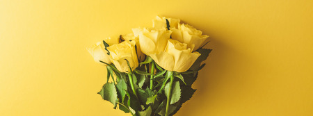 Creative top view flat lay fresh yellow roses bouquet with copy space bold color paper background minimalism style. Template feminine blog social media holiday wedding invitation cardの写真素材