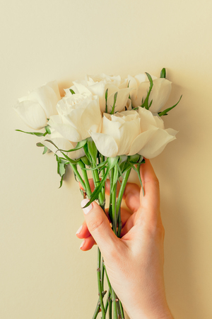 Creative top view flat lay woman hands holding fresh white roses bouquet with copy space pastel paper background minimalism style. Template feminine blog social media holiday wedding invitation cardの写真素材