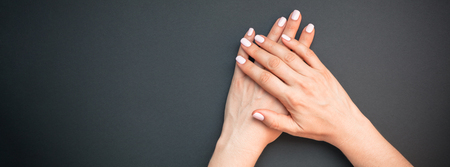 Stylish trendy female pastel pink manicure. Beautiful young woman's hands on black background. Beauty and SPA concept. Template for feminine blog social mediaの写真素材