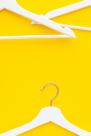 Creative top view flat lay white wooden hangers isolated bold yellow background with copy space minimalism style. Template fashion feminine blog social media sale store promo design shopping conceptの写真素材