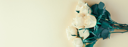 Creative top view flat lay fresh white roses bouquet with copy space pastel paper background minimalism style. Template feminine blog social media holiday wedding invitation cardの写真素材