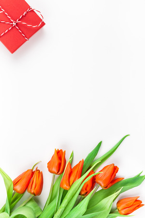 Creative flat lay top view welcome spring greeting card with red tulips flowers on white background with copy space. Celebration Postcard templateの写真素材